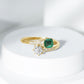 Anillo de compromiso de dos piedras de esmeralda y moissanita con vástago cruzado