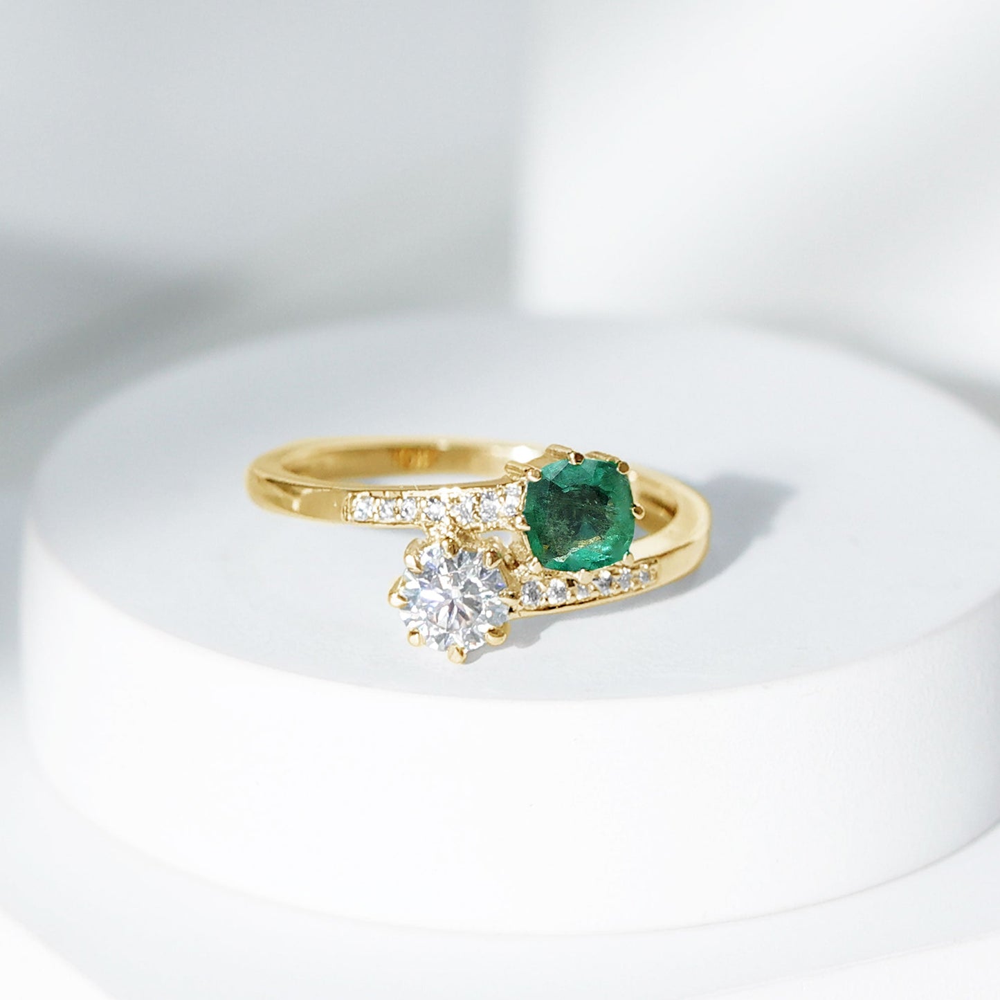 Anillo de compromiso de dos piedras de esmeralda y moissanita con vástago cruzado
