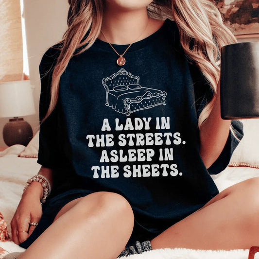 Una dama en las calles, dormida entre las sábanas, camiseta.